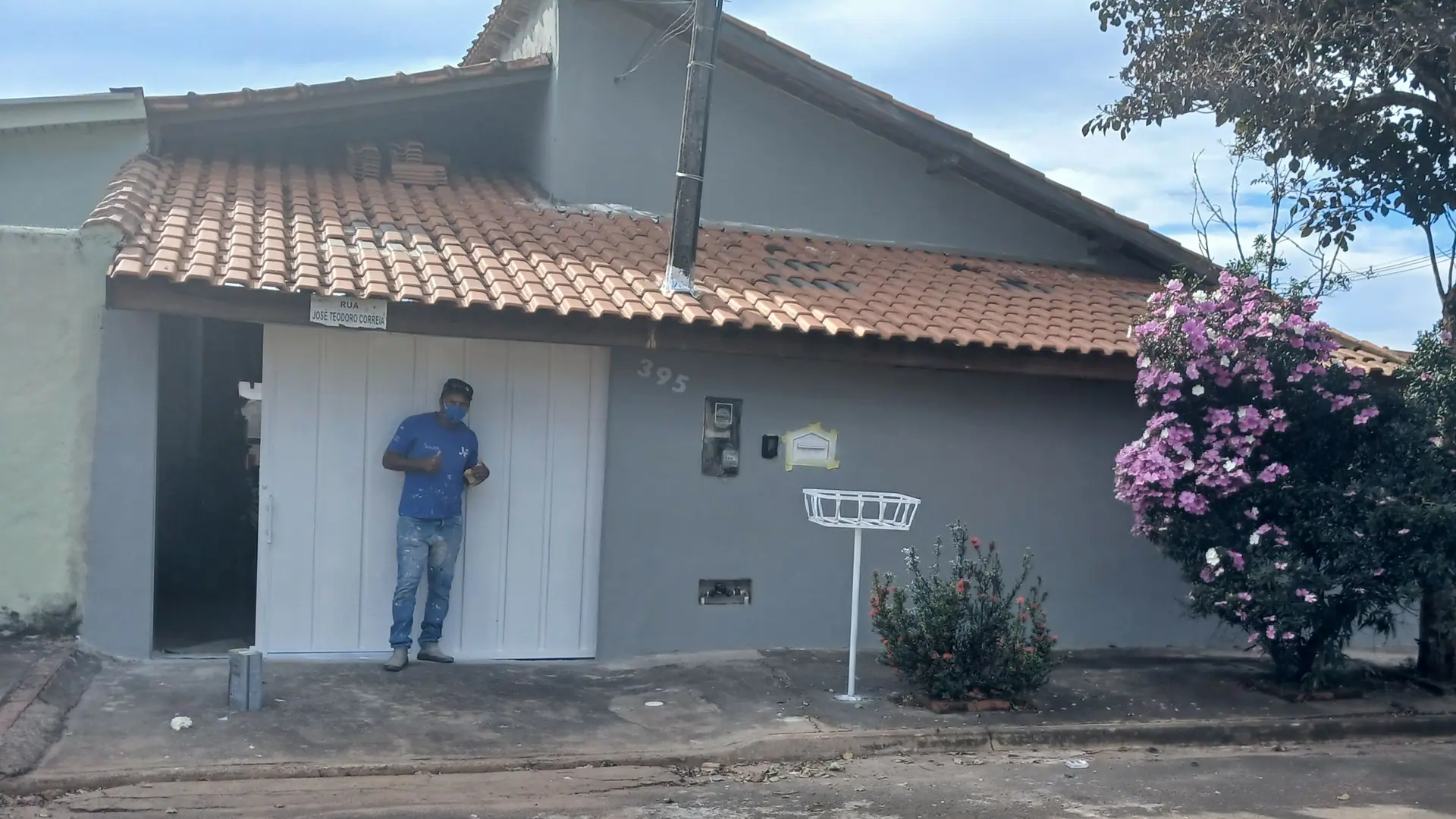 A mesma fachada depois do serviço: parede em cinza uniforme e portão de garagem branco.