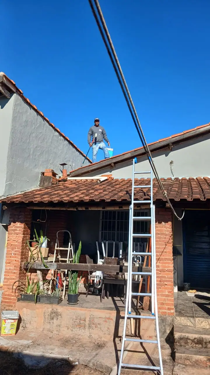 Varanda com pilares de tijolo aparente ainda sem pintura, com escada apoiada no telhado.